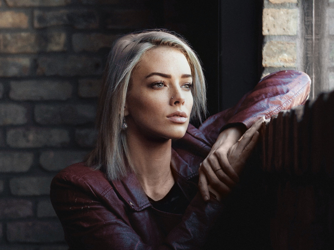 Woman sitting in a dark cafe looking depressed out the window