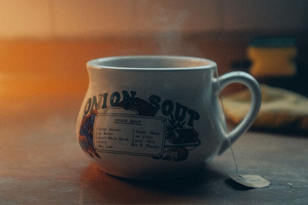 Delicious steaming onion soup for the soul in a ceramic mug that says "Onion Soup" and has a cute little painting on it with the ingredients...of which The Onion is one.