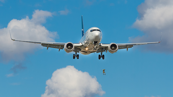 Plane in the sky and clouds with a person pictured jumping below the plane