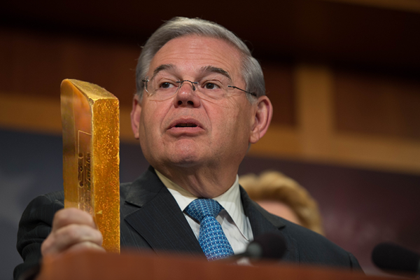 Senator Menendez at podium with a gold bar in hand